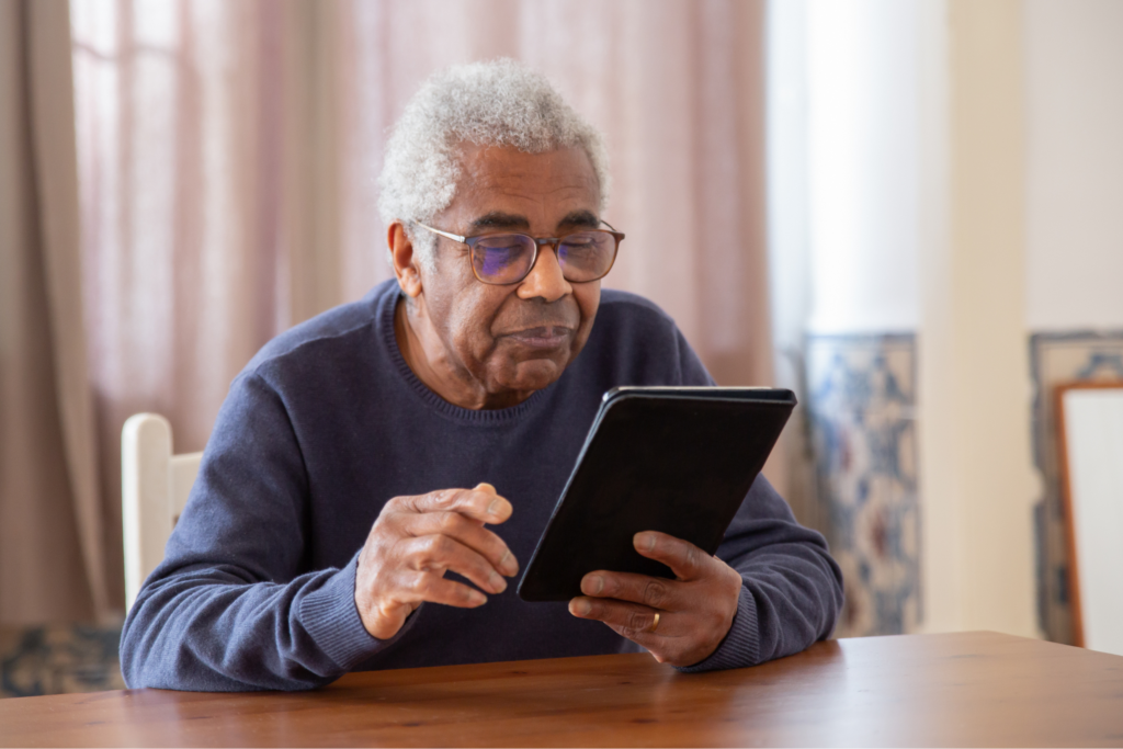 An elderly man looks at a tablet device
