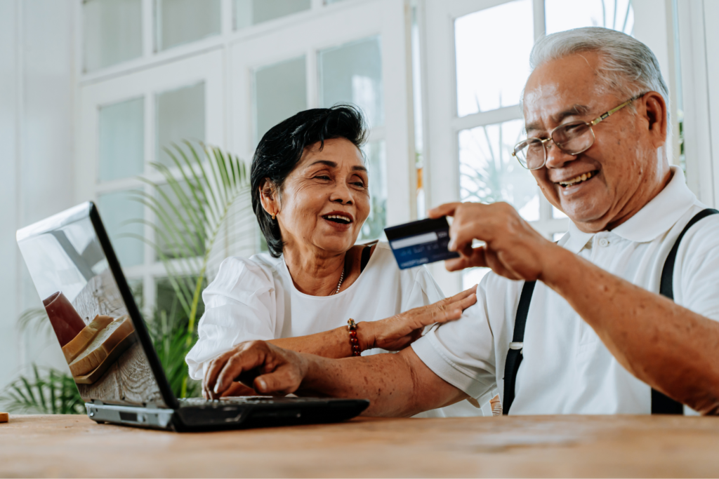 An old couple use a laptop to make a payment.