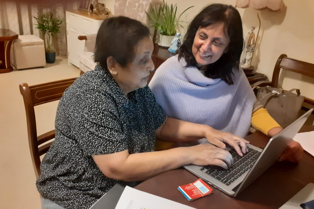 An older woman receiving help to use a laptop