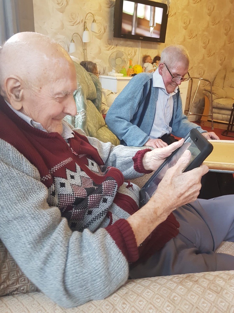 Old man in care home using tablet device