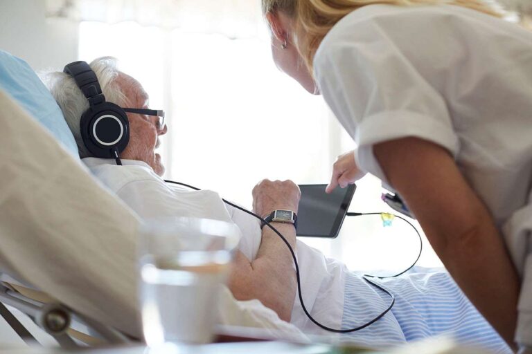 old man on hospital ward using tablet device
