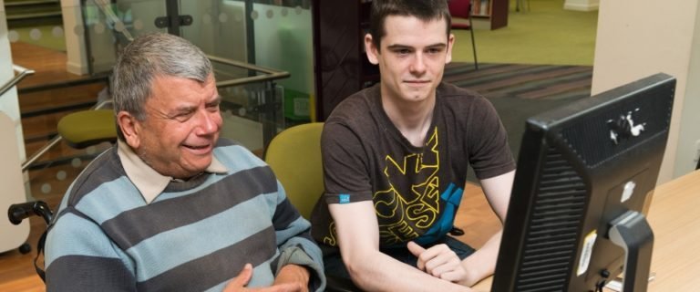 Young man helping an older man with a computer