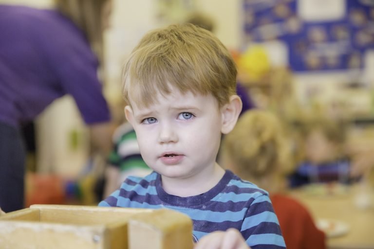 A portrait image of a small boy looking at the camera in nursery.