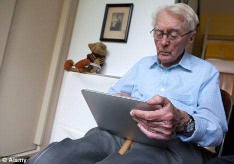 Senior man in a blue shirt looking down onto a tablet device that he's using