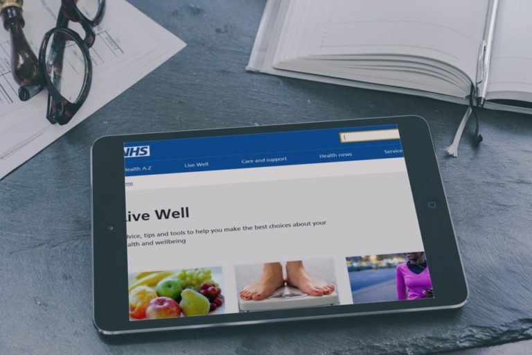 A photograph of a tablet device displaying the NHS Live Well website