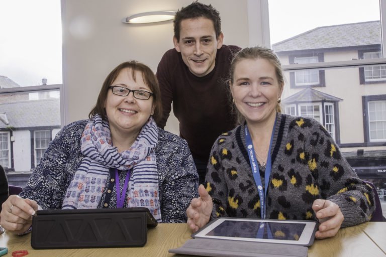 DCW Advisor, Deian ap Rhisiart, and two women with tablets at a digital inclusion training session.