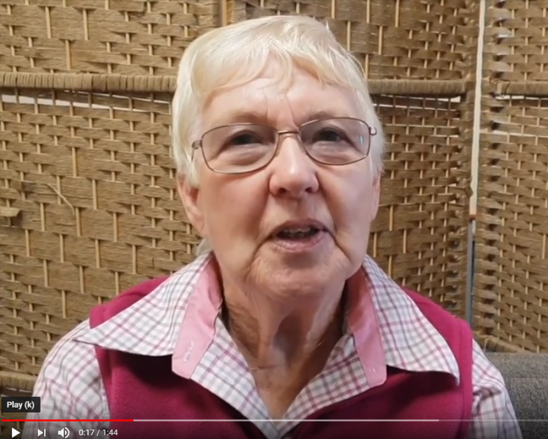 A screenshot of a YouTube video. The image is a headshot of Mary, a volunteer at NEWCIS.