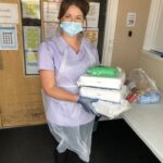 A picture of nurse in PPE carrying tablets