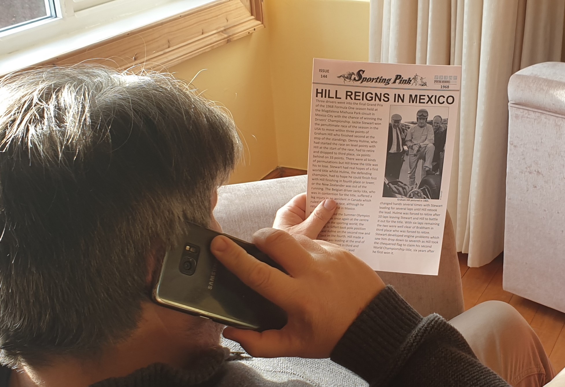 an older man reading an old newspaper article on a sporting event 