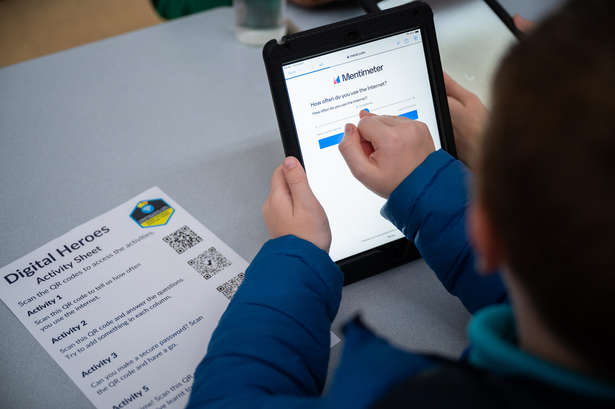 A close up photograph of a Digital Hero using a tablet. They're answering the question 'How often do you use the internet?'