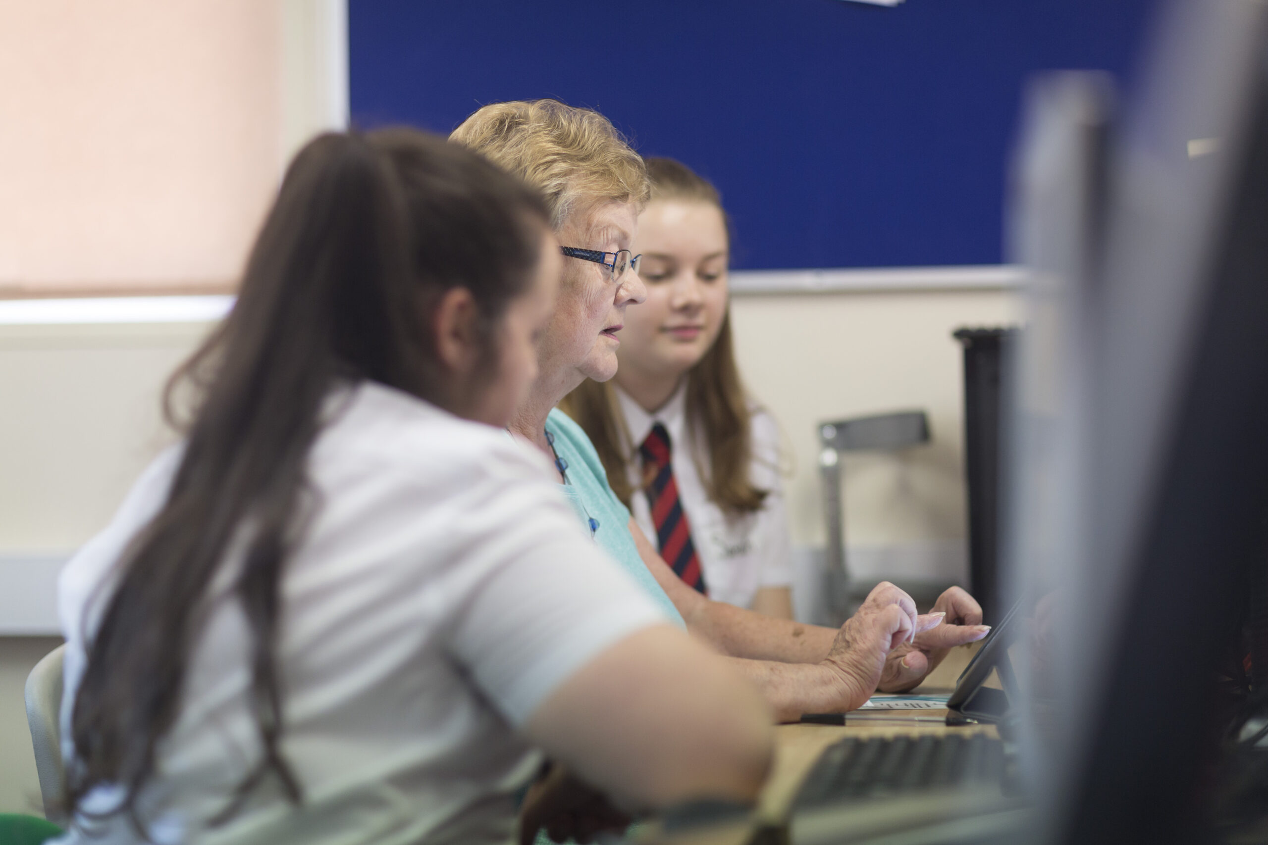 A photograph of two female Digital Heroes supporting an older woman using a computer.