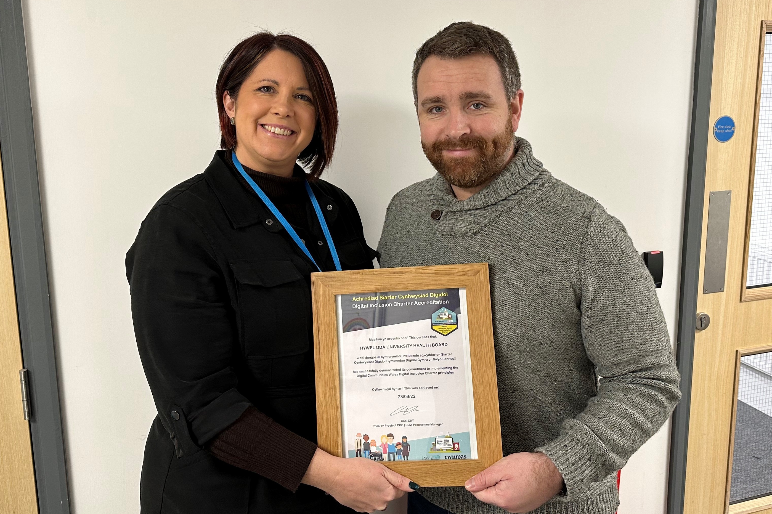 A photograph of a DCW staff member presenting Hywel Dda UHB with an award
