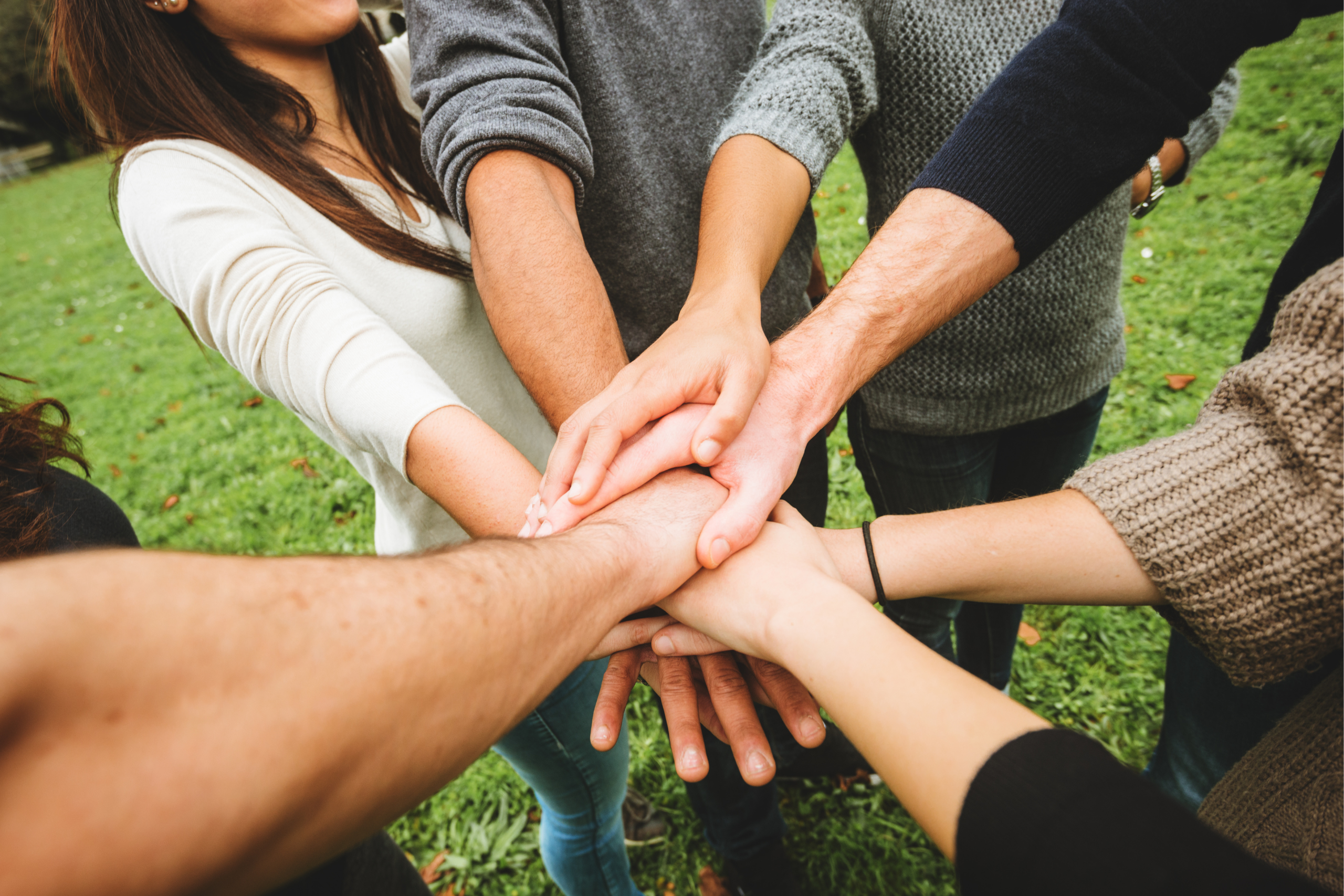 A group of people stack their hands in a circle.