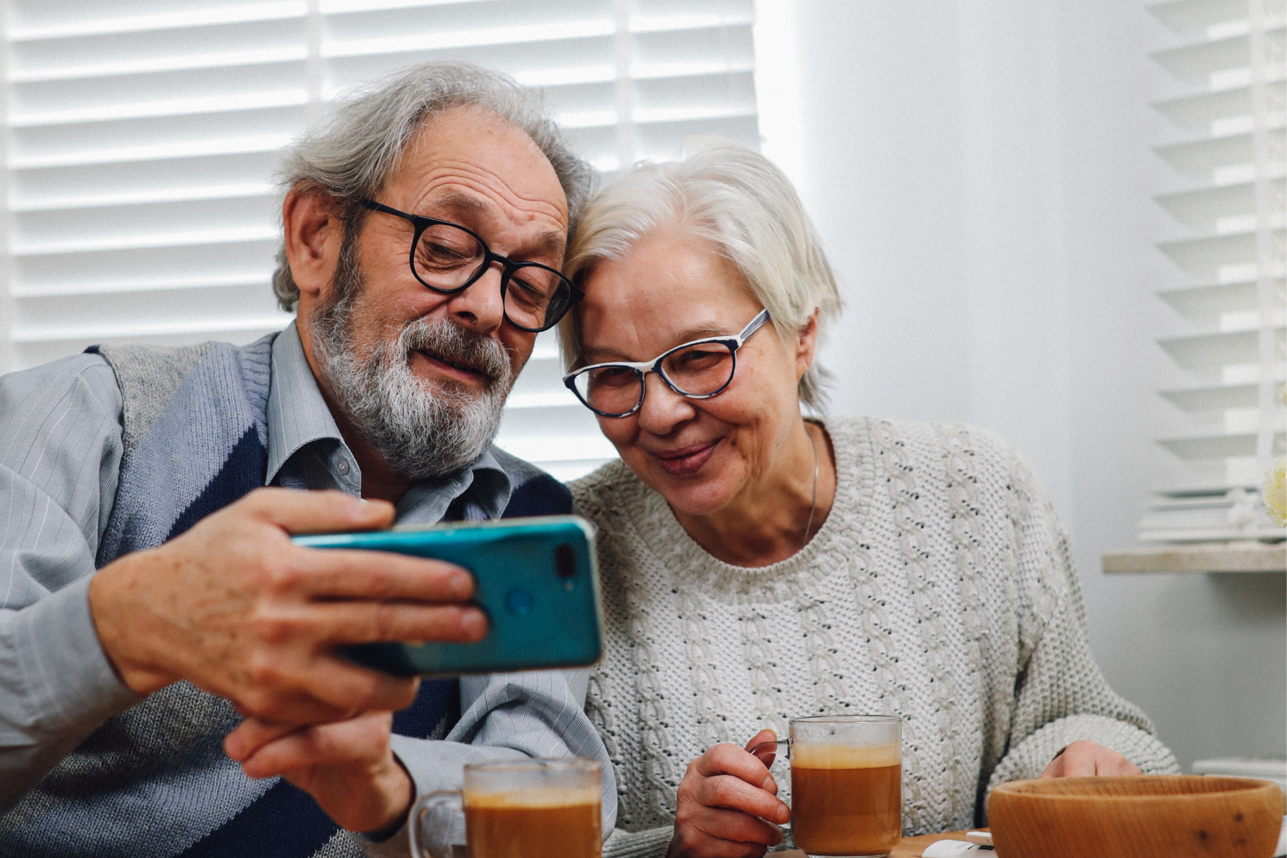 A senior man and woman smile while looking at a mobile device.