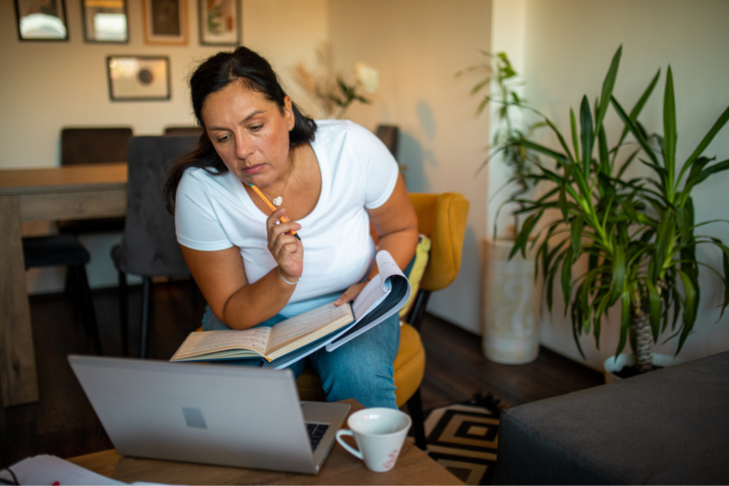 A woman takes notes while learning online