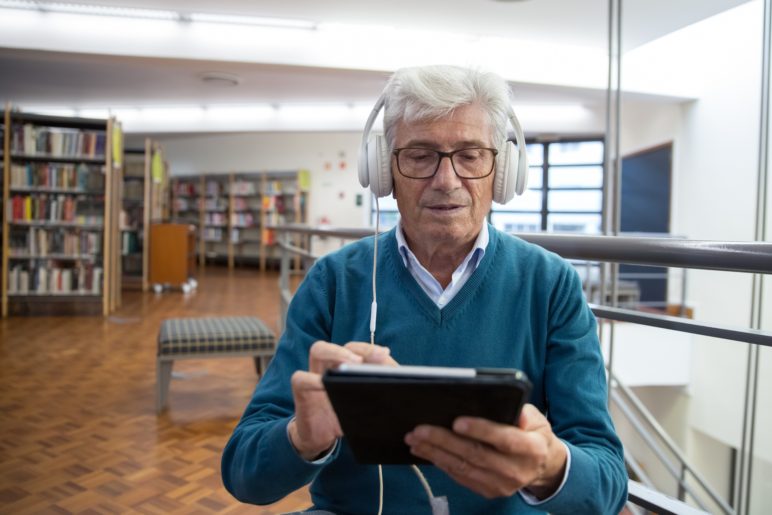 An older man in a library with a tablet