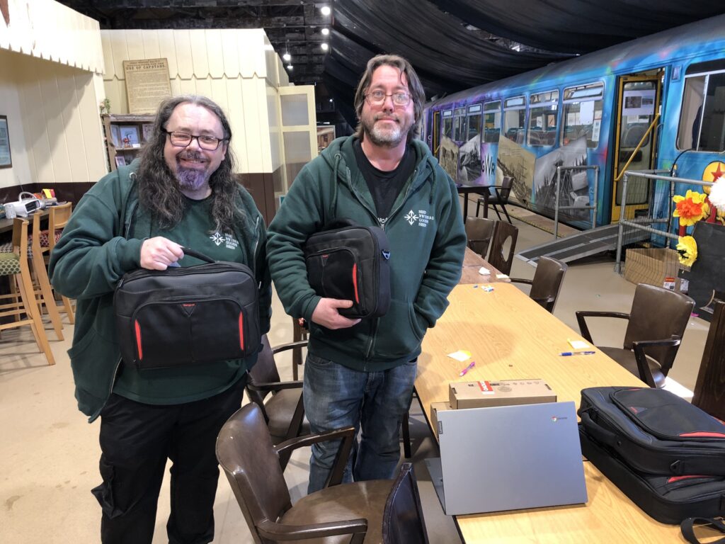 two men in green sweaters with laptop bags